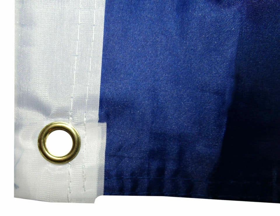 Up of a patriotic American flag showing a metal grommet on the white stripe, used for hanging or mounting the flag securely.